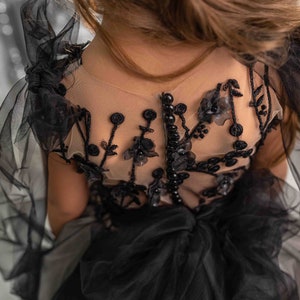 May include: Black tulle dress with floral embroidery and pearl accents. The dress has a sheer bodice and a full skirt. The text "PEARL DRESS BOUTIQUE" is visible at the bottom of the image.