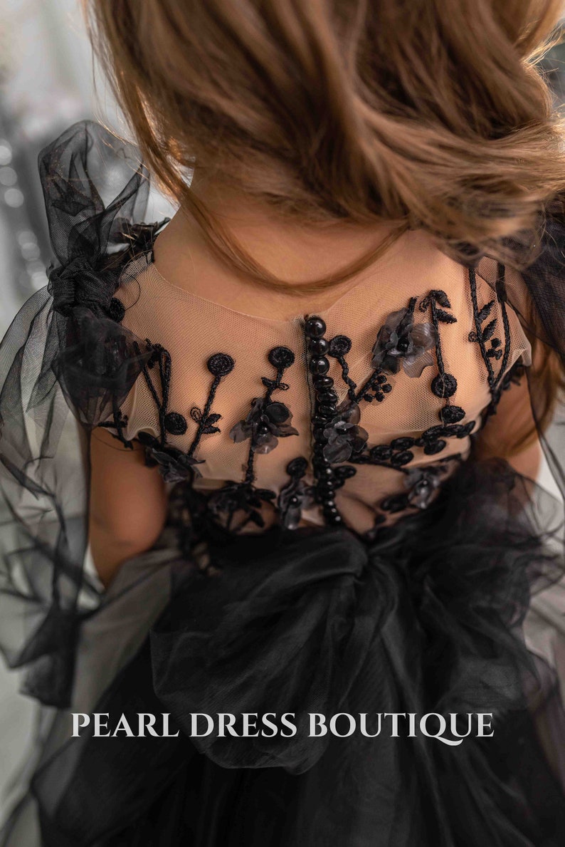 May include: Black tulle dress with floral embroidery and pearl accents. The dress has a sheer bodice and a full skirt. The text "PEARL DRESS BOUTIQUE" is visible at the bottom of the image.