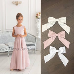 Pu&ograve; includere: Tre fiocchi di raso in bianco e rosa cipria. I fiocchi sono legati con un anello e sono perfetti per aggiungere un tocco di eleganza a qualsiasi occasione.