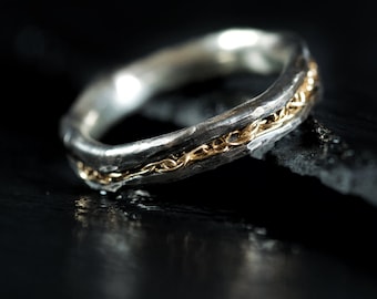 May include: A silver ring with a band of gold chain detail.