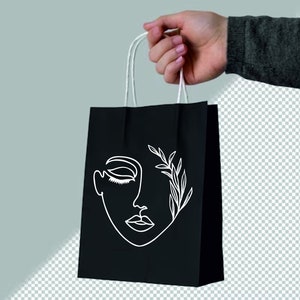 May include: A black paper shopping bag with white line art of a face and leaves. The bag has white handles.