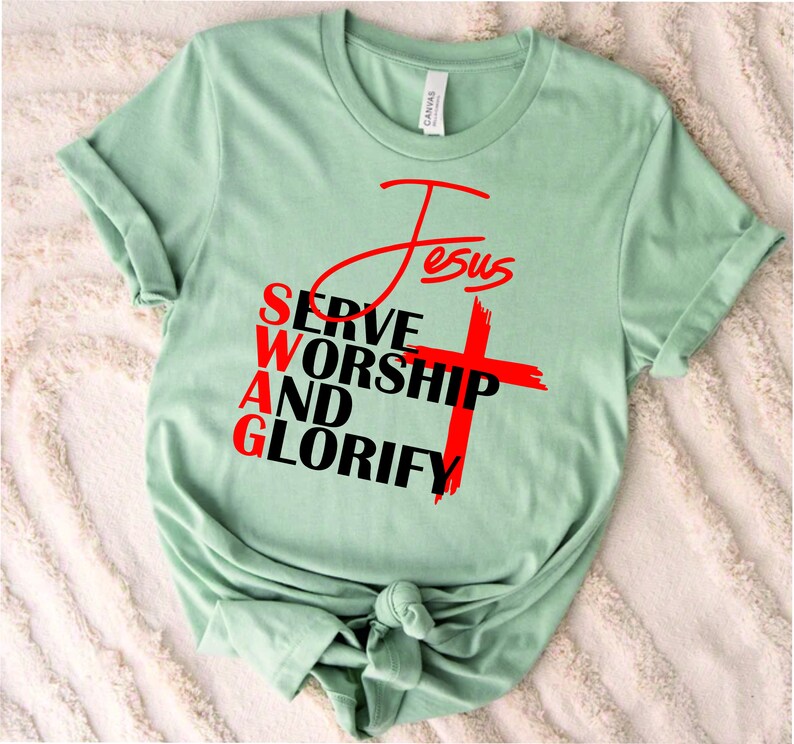 May include: A light green t-shirt with a red cross and the words "Jesus", "Serve", "Worship", "And", and "Glorify" in black.