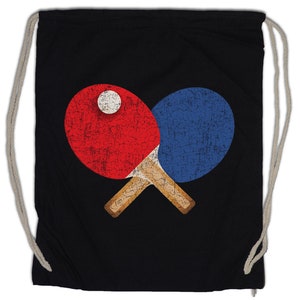 Könnte beinhalten: Schwarze Drawstring-Tasche mit einer Grafik im Vintage-Stil von zwei gekreuzten Tischtennis-Schlägern und einem Ball. Die Schläger sind rot und blau mit weißen Akzenten.