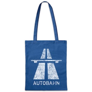 Könnte beinhalten: Eine blaue Tragetasche mit einer weißen, abgenutzten Grafik eines Autobahnkreuzes und dem Wort "Autobahn" darunter. Die Tasche hat zwei lange Griffe zum Tragen.
