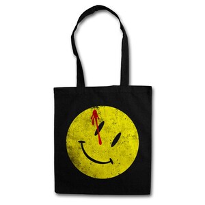 Könnte beinhalten: Schwarze Tragetasche mit einem gelben Smiley-Gesicht mit einem roten Blutspritzer auf der Stirn. Das Smiley-Gesicht ist abgenutzt und hat einen Grunge-Effekt.