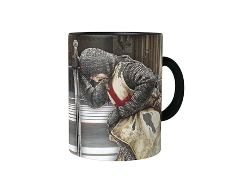 May include: A black and white mug with a design of a knight in armor kneeling with his head bowed. The knight is wearing a red cross on his chest and is holding a sword. The mug has a black handle.