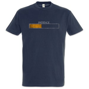 Peut inclure: T-shirt bleu marine avec le mot "PATIENCE" au-dessus d'une barre de progression. La barre est partiellement remplie d'orange, suggérant un concept d'attente ou de chargement. Le t-shirt est de style col rond.