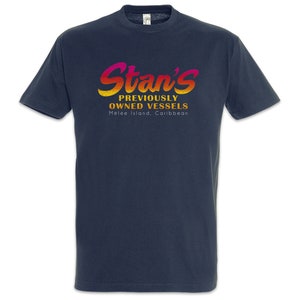 Op de afbeelding: Marineblauw T-shirt met de tekst "Stan's Previously Owned Vessels" in een verloop van roze, oranje en geel. De tekst is gecentreerd, met daaronder "Melee Island, Caribbean".