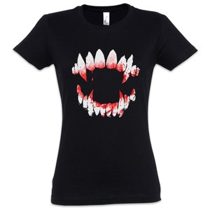 May include: Black t-shirt with a graphic of sharp, white teeth and red blood splatter. The design is centered on the front. The shirt has short sleeves and a crew neck.