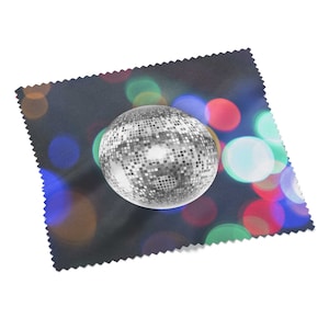 Könnte beinhalten: Eine silberne Discokugel mit einer verspiegelten Oberfläche vor einem dunklen Hintergrund mit bunten verschwommenen Lichtern.