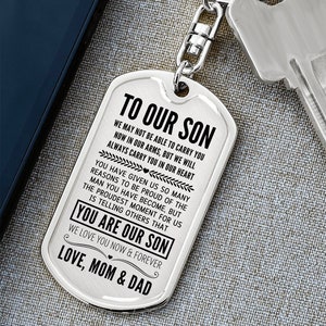 May include: A silver dog tag keychain with the text "TO OUR SON" and a heartfelt message from parents. The keychain is attached to a key and a metal clasp.