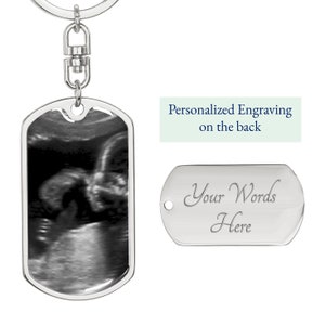 Pu&ograve; includere: Portachiavi in ​​argento con un'immagine di ecografia in bianco e nero sul davanti e un'etichetta in argento vuota sul retro che dice "Le tue parole qui".