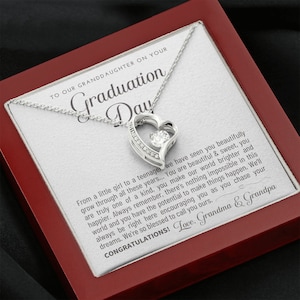 Peut inclure: Un collier pendentif argent&eacute; en forme de c&oelig;ur avec une pierre centrale transparente, pr&eacute;sent&eacute; dans un coffret rouge. Le coffret contient un message imprim&eacute; pour une petite-fille le jour de sa remise de dipl&ocirc;me.