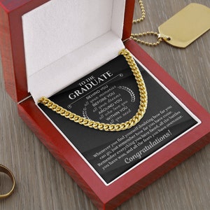 Pu&ograve; includere: Una collana a catena dorata in una scatola rossa con un biglietto nero che recita "Al laureato" con un messaggio di incoraggiamento e congratulazioni.