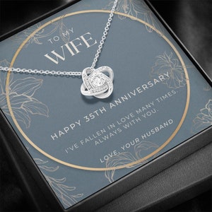 Könnte beinhalten: Eine silberne Halskette mit einem Knotendesign-Anhänger und einem klaren Kristall in der Mitte. Die Halskette befindet sich in einer Geschenkbox mit blauem Hintergrund und dem Text "To My Wife Happy 35th Anniversary I've fallen in love many times. Always with you. Love, Your Husband".