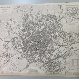 May include: A vintage black and white printed map of Birmingham, England, featuring detailed street layouts, numbered landmarks, and a small inset map in the top right corner. The title BIRMINGHAM is printed in the top left corner of the paper.