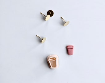 May include: Three gold earring posts with round backs and a pink clay coffee cup charm.