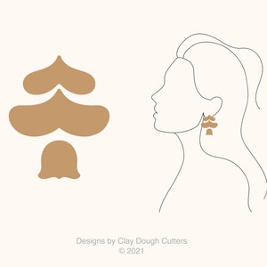 May include: A line drawing of a person wearing a pair of brown earrings shaped like a stylized tree. The earrings are made of three overlapping shapes, each with a heart-shaped top and a rounded bottom. The tree design is also shown separately in the image.