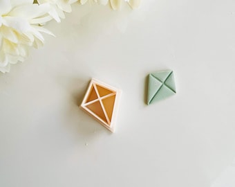 Peut inclure: Deux emportes-pièces en plastique, l'un en forme de diamant et l'autre en forme de cerf-volant. L'emporte-pièce en forme de diamant est rose clair et l'emporte-pièce en forme de cerf-volant est vert clair.