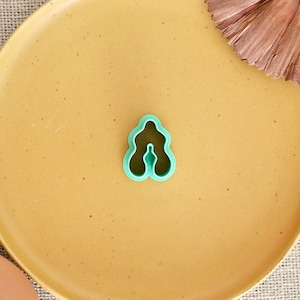 Pode incluir: Um cortador de biscoitos de plástico verde em forma de flor com cinco pétalas.