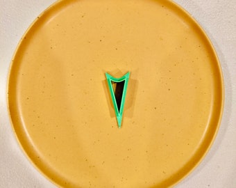 Könnte beinhalten: Ein grüner, dreieckiger Keksausstecher aus Plastik auf einem beigefarbenen, gefleckten Teller.
