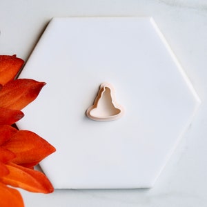 May include: A white plastic cookie cutter shaped like a witch's hat.