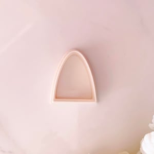 Pode incluir: Um cortador de biscoitos de plástico branco em forma de arco.