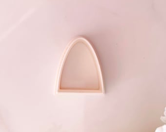 May include: A white plastic cookie cutter shaped like an archway.