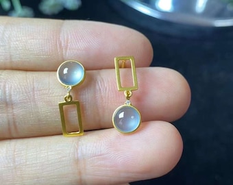 May include: A pair of gold earrings with a light blue gemstone and a rectangular design. The earrings are dangling and have a small diamond accent.
