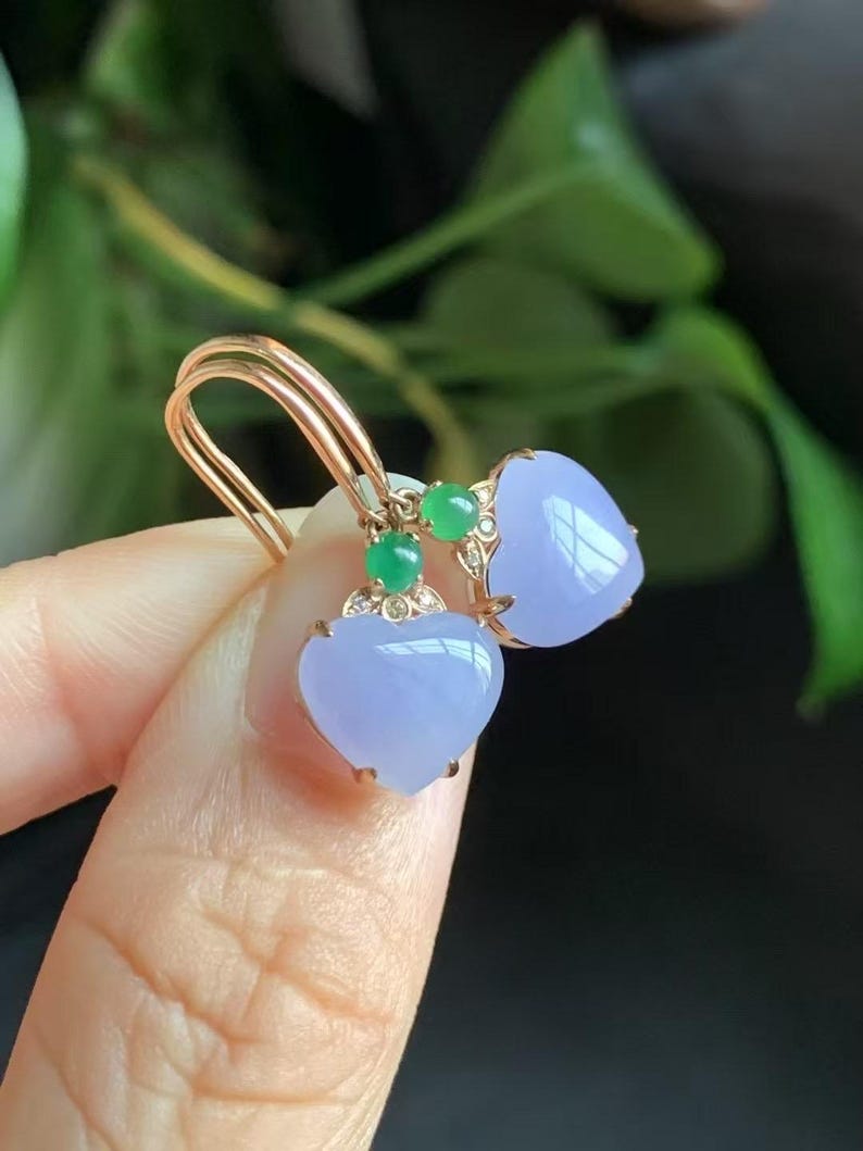 May include: A pair of heart-shaped lavender jade earrings with green jade accents and gold settings.