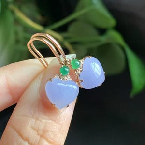 May include: A pair of heart-shaped lavender jade earrings with green jade accents and gold settings.