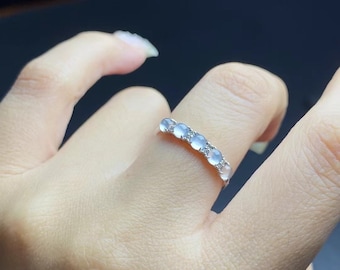 May include: A silver ring with a row of clear, round gemstones set in a band.