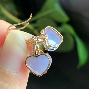 May include: A pair of heart-shaped earrings with lavender-colored stones set in gold.