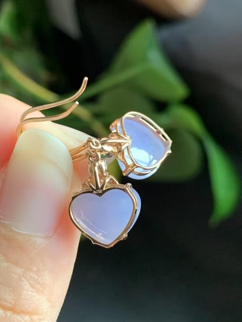 May include: A pair of heart-shaped earrings with lavender-colored stones set in gold.