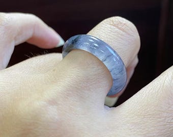May include: A gray jade ring with a smooth, polished finish. The ring is wide and has a rounded shape.