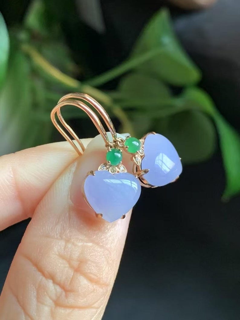 May include: A pair of heart-shaped lavender jade earrings with green jade accents and diamond accents set in gold.