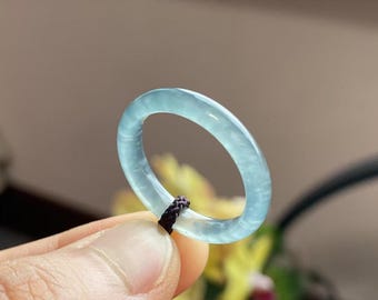 May include: A light blue jade ring with a smooth, polished finish. The ring is made of natural jade and has a delicate, feminine design.