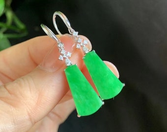 May include: A pair of green jade earrings with diamond accents. The earrings are in the shape of a teardrop and are suspended from a silver hook.