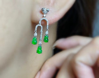 May include: A pair of dangle earrings with a silver setting and three green jade drops. The jade drops are shaped like gourds and are accented with small diamonds.