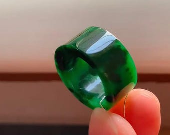Peut inclure: Une bague en résine verte avec un motif marbré. La bague est épaisse et a une forme arrondie.