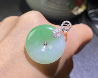 May include: A green jade pendant with a white jade center and a diamond accent. The pendant is attached to a silver chain with a diamond-encrusted bail.