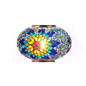 Op de afbeelding: Een ronde, kleurrijke mozaïek glazen lamp met een stervormig ontwerp in tinten blauw, geel, rood en groen. De lamp is aan en het licht schijnt door het glas.