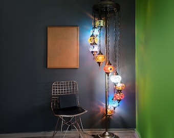 May include: A tall, gold floor lamp with a spiral design. The lamp has multiple colorful glass globes with intricate mosaic patterns. The globes are lit and cast a warm glow.