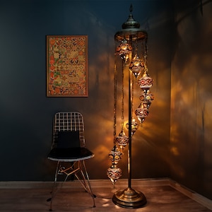 May include: A gold floor lamp with a spiral design and multiple stained glass globes. The lamp is lit and casting a warm glow.