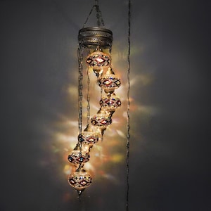 May include: A cascading chandelier with six colorful glass globes, each with a geometric pattern. The globes are suspended from a metal frame with chains.