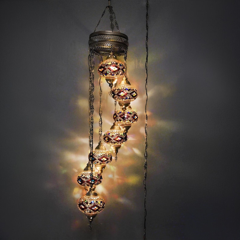 May include: A cascading chandelier with six colorful glass globes, each with a geometric pattern. The globes are suspended from a metal frame with chains.