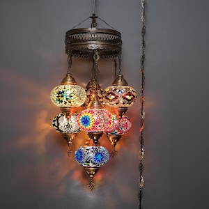 May include: A multi-tiered chandelier with six colorful mosaic glass globes. The globes are in shades of blue, green, red, yellow, and white. The chandelier has a brass finish and is suspended from a chain.