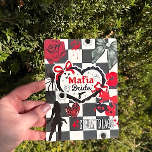 May include: A rectangular card with a black and white checkered pattern, featuring red roses, bows, and a spiderweb design. The words "Mafia Bride" are displayed in a heart-shaped design, along with a silhouette of a woman holding a gun.