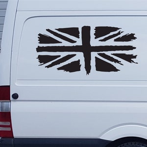 May include: A white van with a black distressed Union Jack flag decal on the back window.
