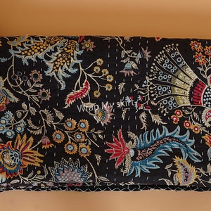 May include: Black kantha quilt with a floral pattern in shades of red, blue, yellow, and gold. The quilt is made of cotton and has a hand-stitched design.